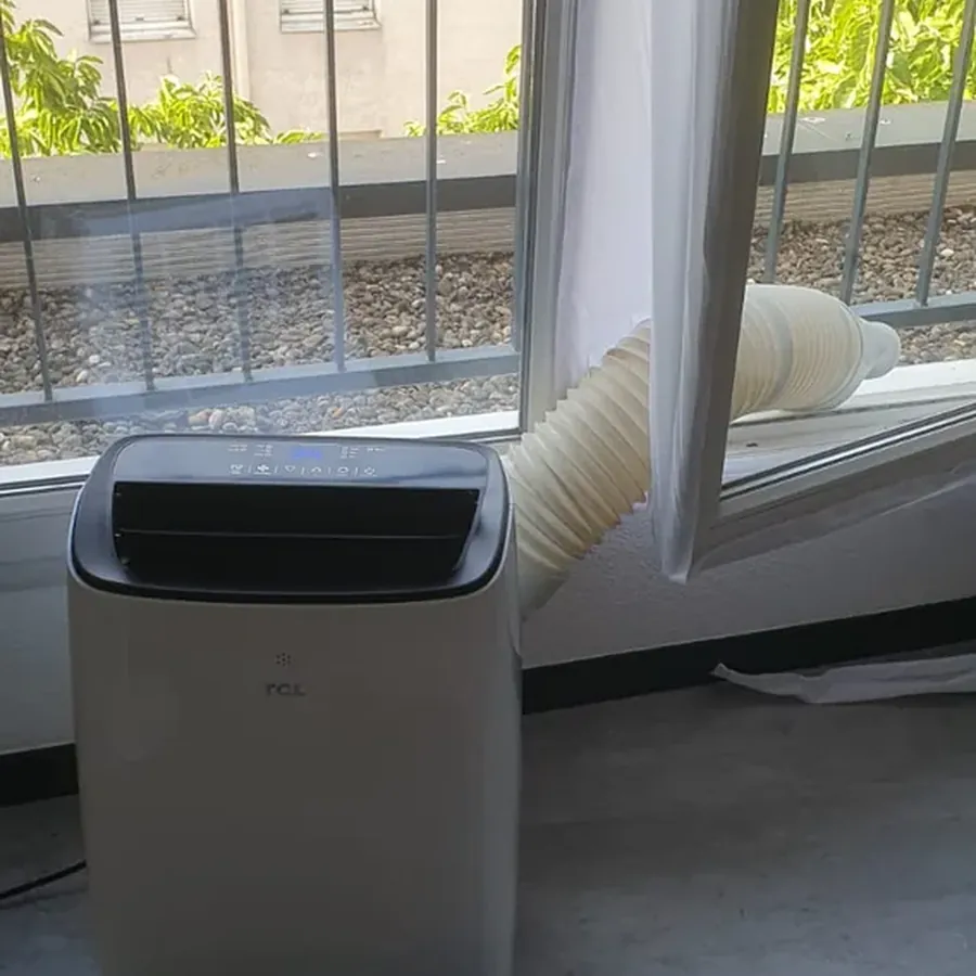 Climatiseur mobile installé devant une fenêtre dans une chambre à Lyon