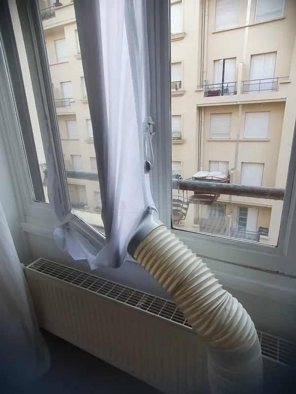 Tuyau d'évacuation d'un climatiseur mobile raccordé à la fenêtre avec un kit de calfeutrage, à Lyon