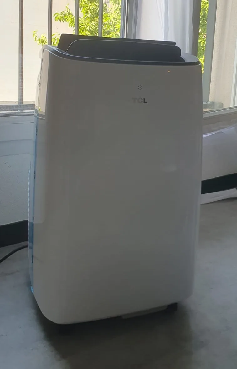 Climatiseur mobile TCL installé devant une fenêtre, loué et livré à Lyon par LouerMaClim